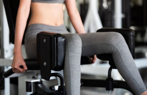 kvinde bruger maskine til træning af sine abductor-muskler