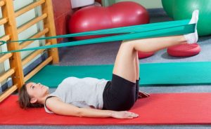 Kvinde laver øvelser med træningselastik.