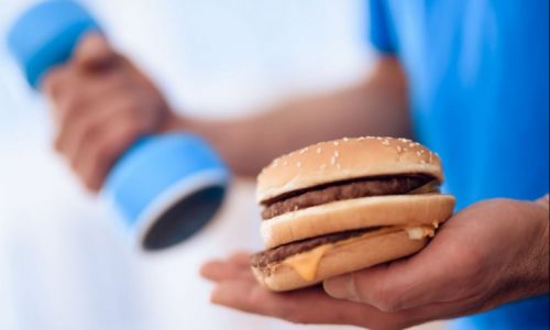 Mand træner med burgr i hånden