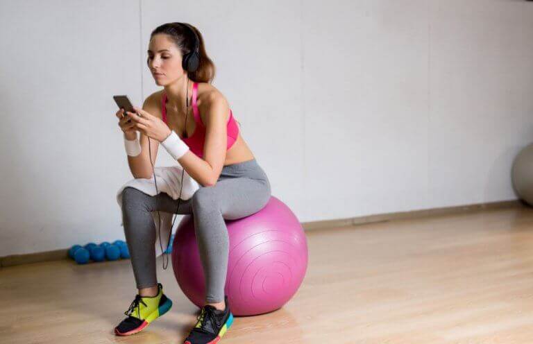 kvinde der bruger sin mobil på træningsbold