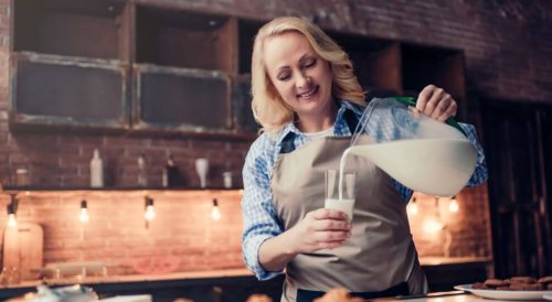 kvinde der hælder mælk i glas