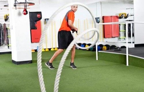 Mand træner med battle ropes i fitnesscenteret