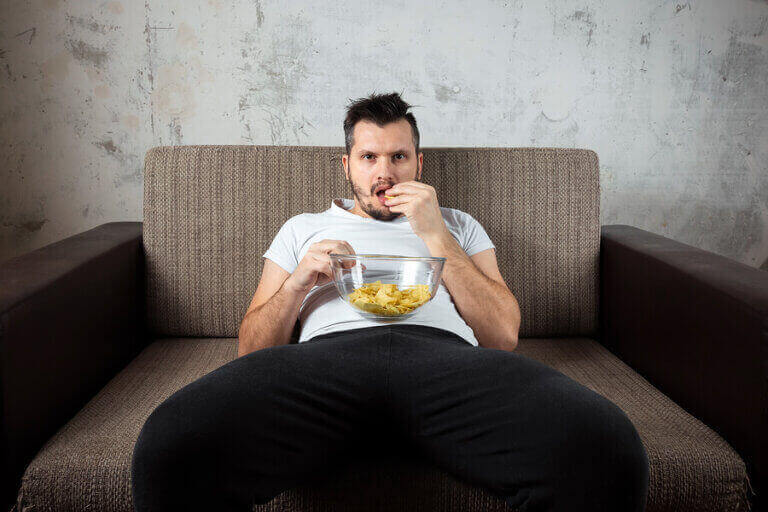 mand der spiser chips i sofa